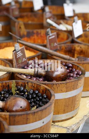 Varietà di olive assortite esposte in botti di legno rustico al mercato locale Stall. Salisbury, Inghilterra Foto Stock