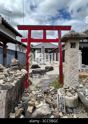 Uno stretto torrente urbano che scorre attraverso un quartiere residenziale a Kyoto, in Giappone, sotto un cielo coperto. Foto Stock