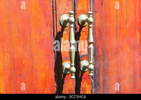 Porte in legno con agenti atmosferici, accentuate da maniglie in metallo antico. Porta vecchia con eleganti maniglie in stile antico Foto Stock