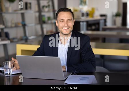 Allegro e di successo, bel manager di prodotto latino che lavora al notebook Foto Stock