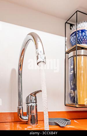 Utensili abbandonati sotto l'acqua corrente, come se qualcuno fosse fuggito dalla cucina, lasciando il caos alle spalle Foto Stock