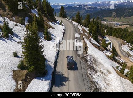 Auto su tortuosa strada di montagna, circondata da neve e abeti, con ampia vista, vista aerea, camper, camper, sulla strada per il passo di Goderdzi, Adjara Re Foto Stock