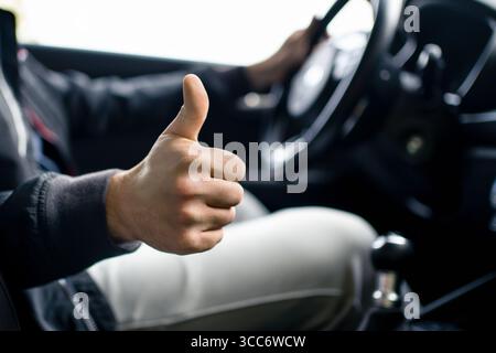 Autista di taxi. Guida sicura. Buon servizio di licenza. Pollice in alto. Cliente soddisfatto in concessionaria. Guida o auto condivisa. Al chiuso, all'interno del veicolo. Foto Stock