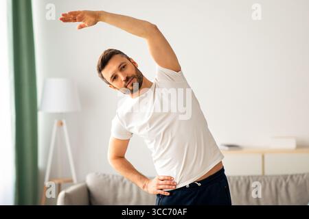 Atletico uomo di mezza età in abbigliamento sportivo che si esercita a casa Foto Stock