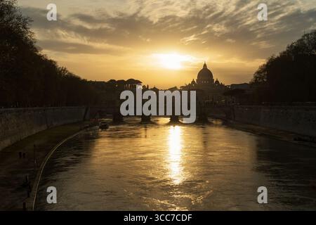 Vista al tramonto della Basilica di San Pietro e del Tevere che riflette la luce dorata di Roma. Foto Stock