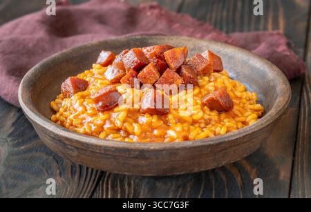 Risotto sostanzioso con chorizo, pomodori maturi ed erbe aromatiche servito in un rustico recipiente in ceramica Foto Stock