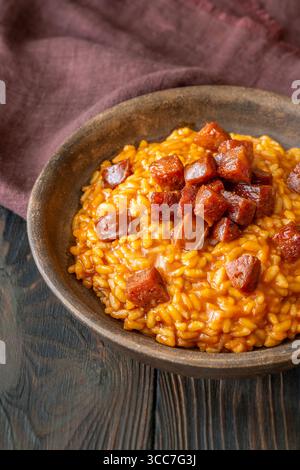 Risotto sostanzioso con chorizo, pomodori maturi ed erbe aromatiche servito in un rustico recipiente in ceramica Foto Stock