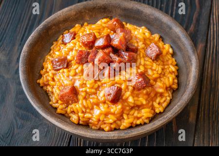 Risotto sostanzioso con chorizo, pomodori maturi ed erbe aromatiche servito in un rustico recipiente in ceramica Foto Stock