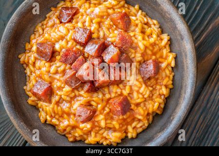 Risotto sostanzioso con chorizo, pomodori maturi ed erbe aromatiche servito in un rustico recipiente in ceramica Foto Stock