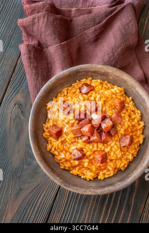 Risotto sostanzioso con chorizo, pomodori maturi ed erbe aromatiche servito in un rustico recipiente in ceramica Foto Stock