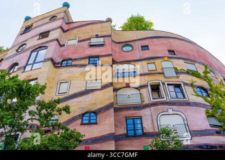 Facciata colorata del complesso residenziale Waldspirale caratterizzata da elementi architettonici unici, linee curve e vivaci sfumature completate da un ambiente più verde Foto Stock