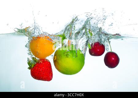 Spruzzi dinamici di frutta fresca assortita, tra cui fragole, ciliegie dolci, albicocche e lime, che creano un vivace effetto acqua su un dorso luminoso Foto Stock