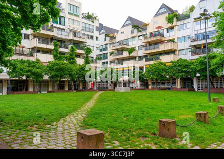 Colonia, Germania - 15 giugno 2025: Lussureggiante cortile verde circondato da condomini contemporanei con balconi e grandi finestre Foto Stock