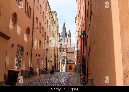 Colonia, Germania - 15 giugno 2025: Stretta strada acciottolata di Colonia incorniciata da edifici colorati e guglie storiche. Foto Stock