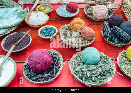 Un'immagine vibrante con una collezione di materiali di tintura naturali e palle di lana tradizionalmente utilizzate nella produzione tessile andina Foto Stock
