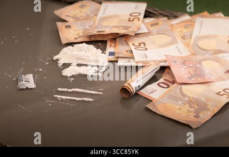 Una pila di farmaci falsi fatti di farina e banconote in euro modificate poste su un tavolo. Immagine concettuale che rappresenta attività illegali, simulato traffico di droga Foto Stock