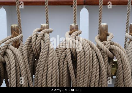 Corda nautica intemprata legata a un Cleat su una nave di legno Foto Stock