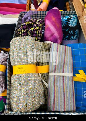 Padova, Italia - 18 aprile 2025: Colorato assortimento di tessuti esposti in un cesto intrecciato, con varie texture e motivi per cucire e cr Foto Stock