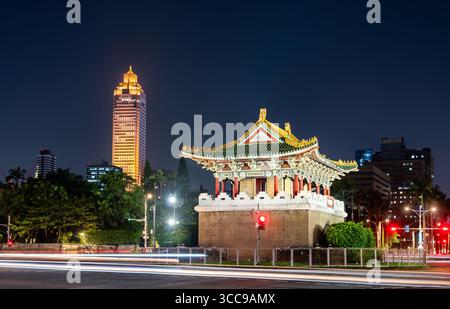 La storica porta di Jingfu (porta Est) in un cerchio di traffico di notte, con il moderno skyline della città di Taipei e sentieri a semaforo sullo sfondo, Taiwan Foto Stock