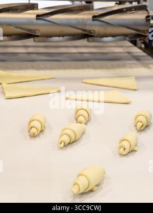 Croissant appena fatti stesi su un bancone della cucina pronti per la cottura in un forno luminoso e moderno alla luce del mattino Foto Stock