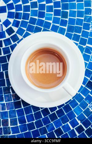 Espresso appena estratto in tazza bianca sul tavolo con mosaico blu Foto Stock