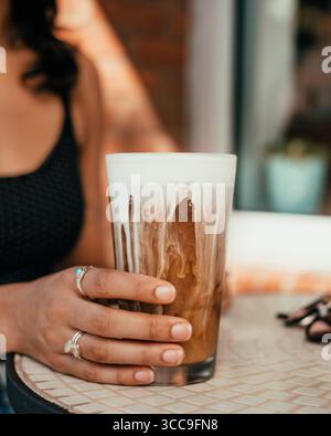 Latte freddo con crema e occhiali da sole sul Café Table Foto Stock