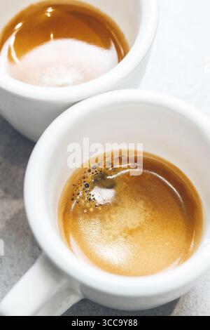 Primo piano di due tazze da caffè bianche con crema pregiata servite sul piano, vista dall'alto Foto Stock