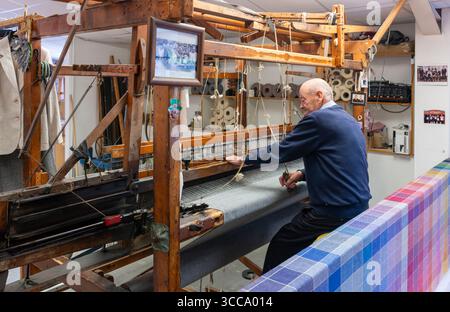 Mastro tessitore intreccia tweed Donegal al Triona Donegal Tweed Centre di Ardara, Donegal, Irlanda, ampia vista del telaio con utensili e rotoli di tessuto Foto Stock