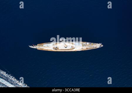 Idra, Grecia - 30 luglio 2025: Veduta aerea di uno yacht bianco scintillante che attraversa il mare blu profondo, un netto contrasto di lusso con la vasta distesa dell'oceano. Foto Stock