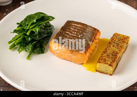Filetto di salmone scottato servito con spinaci saltati e croquette di patate Foto Stock