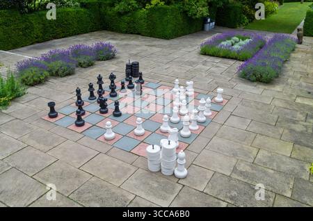 Grande scacchiera all'aperto ambientato al Falkland Palace, in Scozia, con pezzi giganti disposti su un tabellone da giardino, ma nessuna persona visibile Foto Stock