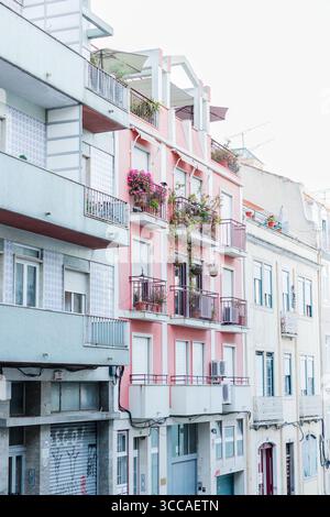 Edificio di appartamenti rosa con balconi e fiori a Lisbona Foto Stock