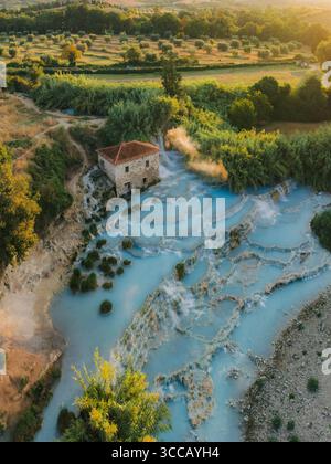 Vista aerea delle cascate, acque azzurre in contrasto con la struttura rustica in pietra e il verde circostante, Saturnia, Toscana, Italia. Foto Stock