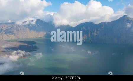 Vista aerea della maestosa caldera del Monte Rinjani, il suo lago turchese che rispecchia l'eterea danza del cielo con le nuvole, Lombok, West Nusa Tenggara, Foto Stock