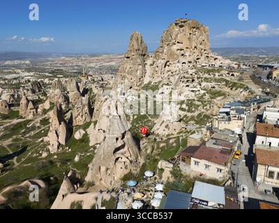 Combinazione di formazioni rocciose ed edifici moderni sotto un cielo blu in una città turca, vista aerea, castello di Uchisar, Uchisar Kalesi, impressionante roccia Foto Stock