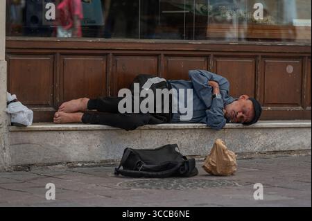 Chania, Creta, Grecia - 22 giugno 2025: Un uomo dorme sul marciapiede a Chania, Creta, mostrando la tranquillità della vita di strada. Foto Stock