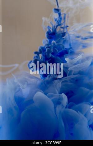 Un'immagine astratta affascinante con un inchiostro blu brillante che diffonde e scorre in acque cristalline Foto Stock