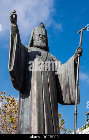 Un piccione seduto in cima alla statua dell'arcivescovo Damaskinos in Piazza Mitropoleos, Atene, Grecia Foto Stock