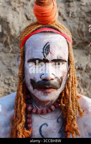 Chandanath Hill, Bangladesh - 12 marzo 2021: Veduta di un uomo con sognatori arancioni vibranti e sorprendente vernice bianca per il viso, uno sguardo intenso che penetra attraverso i colori contrastanti. Foto Stock
