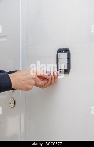 Mani di un elettricista che installa un interruttore elettrico. Foto Stock