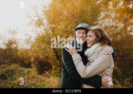 Passeggiata romantica attraverso la foresta autunnale con una coppia anziana. Foto Stock