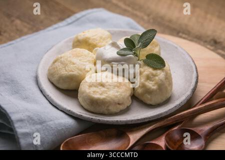 Piatto tradizionale ucraino: Gnocchi pigri realizzati con morbido formaggio fresco con succose ciliegie all'interno. Cucina casalinga, deliziosa e facile da preparare Foto Stock