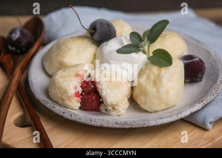 Piatto tradizionale ucraino: Gnocchi pigri realizzati con morbido formaggio fresco con succose ciliegie all'interno. Cucina casalinga, deliziosa e facile da preparare Foto Stock