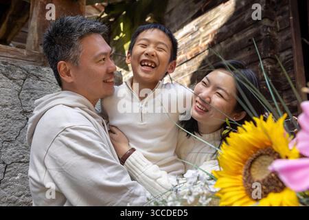 La famiglia asiatica felice si sta abbracciando e sorridendo alla telecamera Foto Stock
