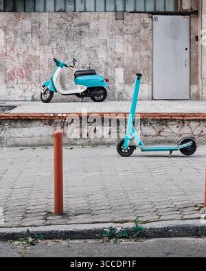 Differenza tecnologica: Due scooter blu parcheggiati per strada. Vista laterale dello scooter elettrico e del ciclomotore dello stesso colore. Foto Stock