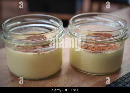 Un paio di vasetti da dessert riempiti con un dessert cremoso, guarniti e pronti per essere serviti. Foto Stock