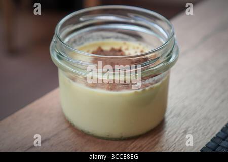 Un unico vasetto di vetro riempito con un dessert cremoso ricoperto di briciole e pronto da mangiare. Foto Stock