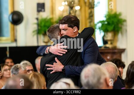 Un destinatario del Purple Heart accoglie un altro partecipante durante una cerimonia della Casa Bianca in onore dei membri del servizio militare in occasione del National Purple Heart Day. Washington, DC. 7 agosto 2025. Per gentile concessione della Casa Bianca. Foto Stock