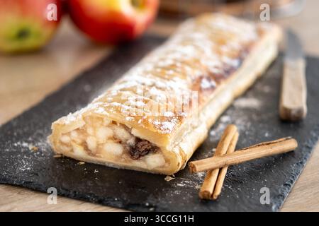 Strudel di mele fatto in casa appena sfornato su un tavolo da servizio in ardesia nera. Foto Stock