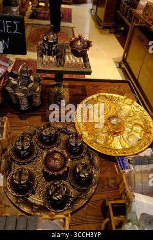 Una gamma di set da tè e caffè in ottone e rame, tra cui piccole tazze e vassoi decorativi, esposti in un negozio, a Salonicco. Foto Stock